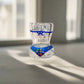 Clear glass object with colorful design and blue ribbon on a white surface