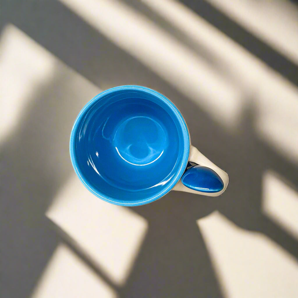 Blue ceramic cup on a metallic surface with a beige background
