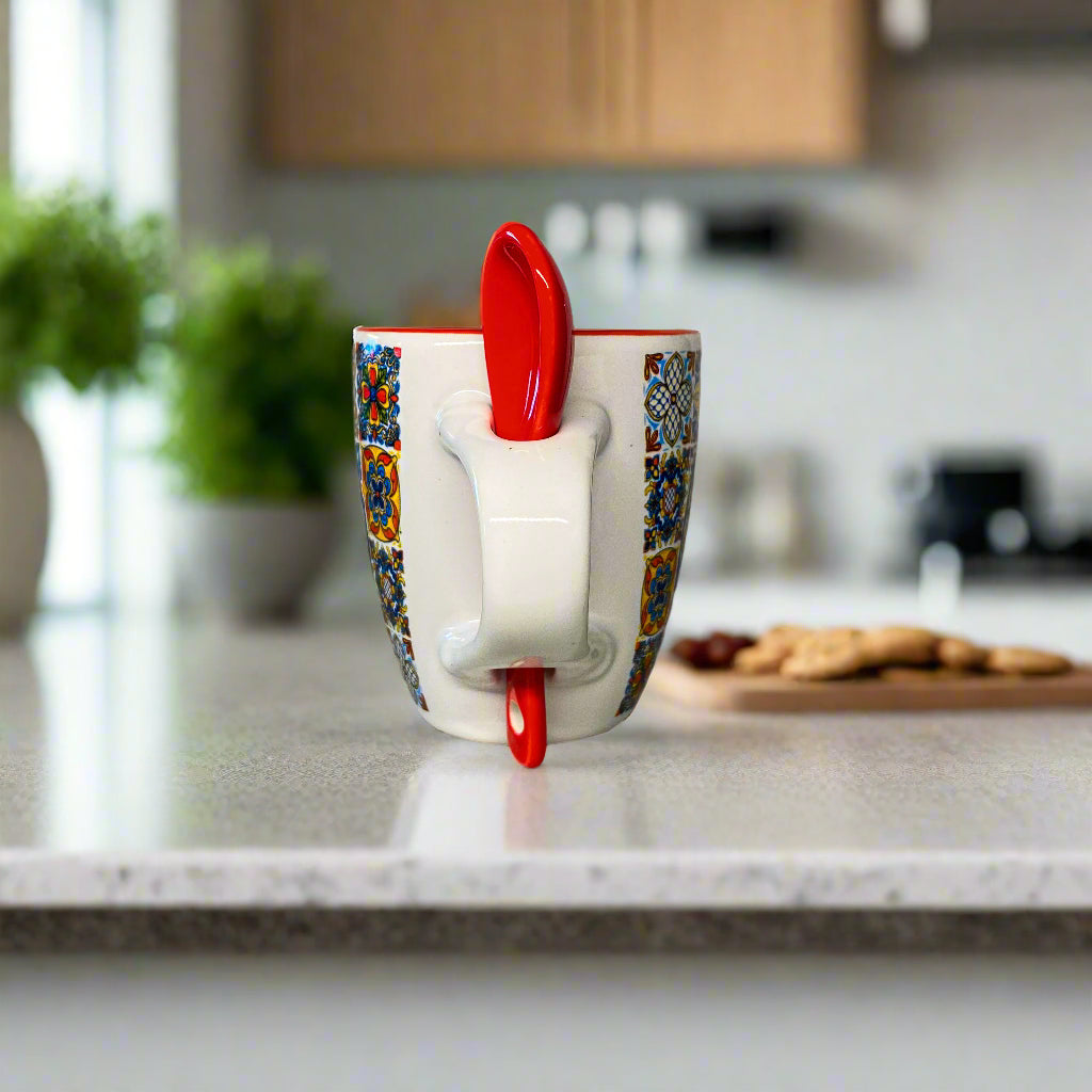 Colorful mug with a red spoon on a white surface