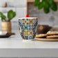 Colorful patterned mug with a red handle on a plain surface