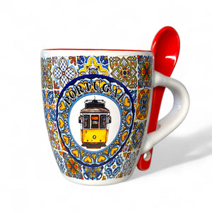 Decorative mug with a tram design and 'Portugal' text, accompanied by a red spoon.