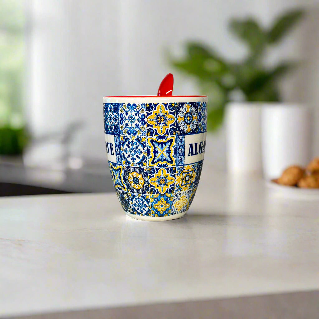 Ceramic mug with colorful pattern and red spoon on a white surface