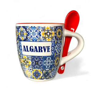 Mug with blue and yellow pattern and red spoon on a white background