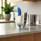 Decorative mug with a blue handle on a plain surface