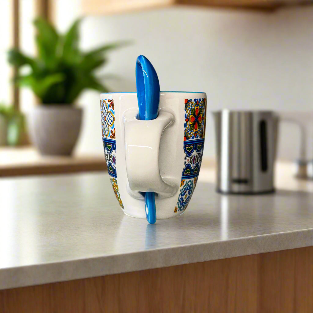 Decorative mug with a blue handle on a plain surface