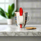 Colorful mug with a red spoon on a white surface