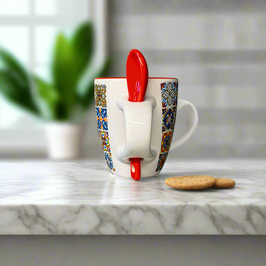 Colorful mug with a red spoon on a white surface
