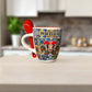 Colorful mug with 'Portugal' text and patterns, accompanied by a red spoon on a light surface.