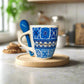 Mug with blue and white pattern and a spoon on a light surface