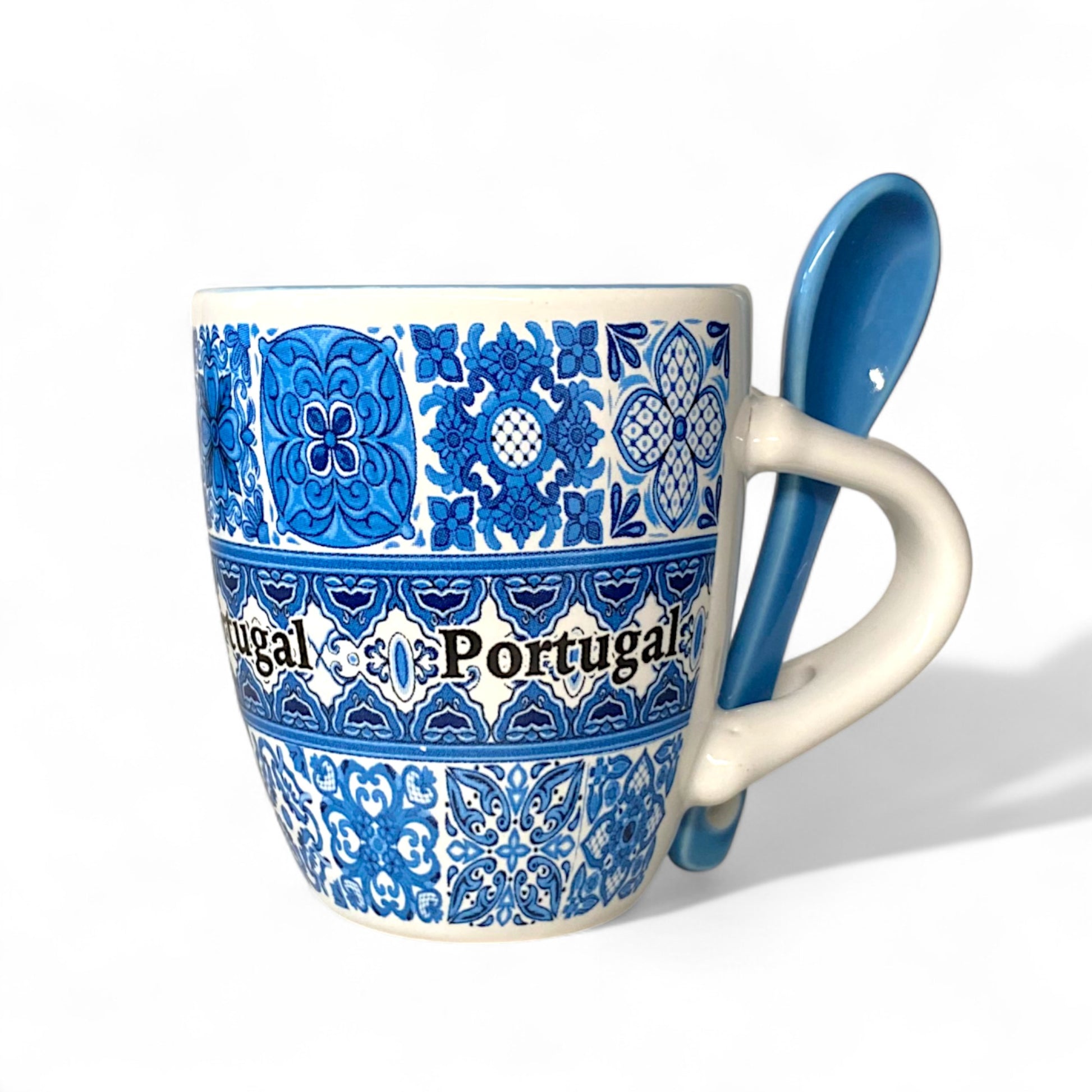 Mug with blue floral patterns and 'Portugal' text, accompanied by a matching spoon on a white background.