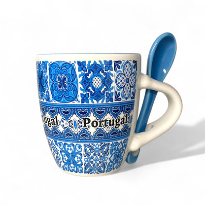 Mug with blue floral patterns and 'Portugal' text, accompanied by a matching spoon on a white background.
