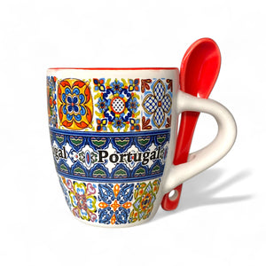 Decorative mug with colorful patterns and a red spoon on a white background