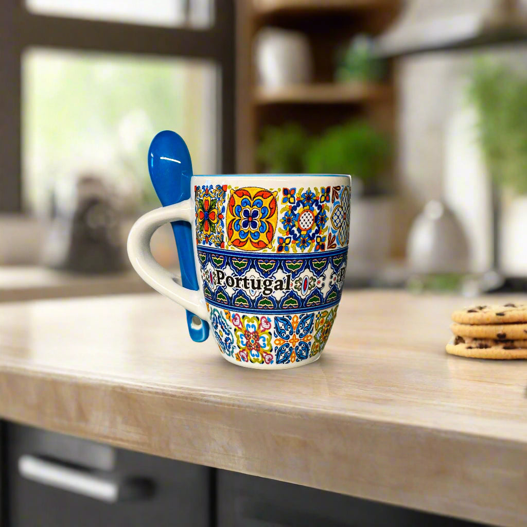 Decorative mug with 'Portugal' text and colorful patterns, accompanied by a blue spoon on a neutral background.