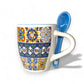 Decorative mug with colorful patterns and a blue spoon on a white background
