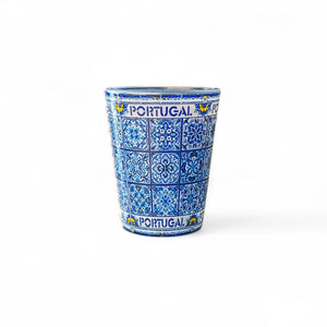 A shot glass with traditional blue azulejo tile pattern and the text 'PORTUGAL' on the side.