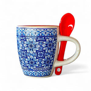 Ceramic coffee cup with blue pattern and red spoon on a white background