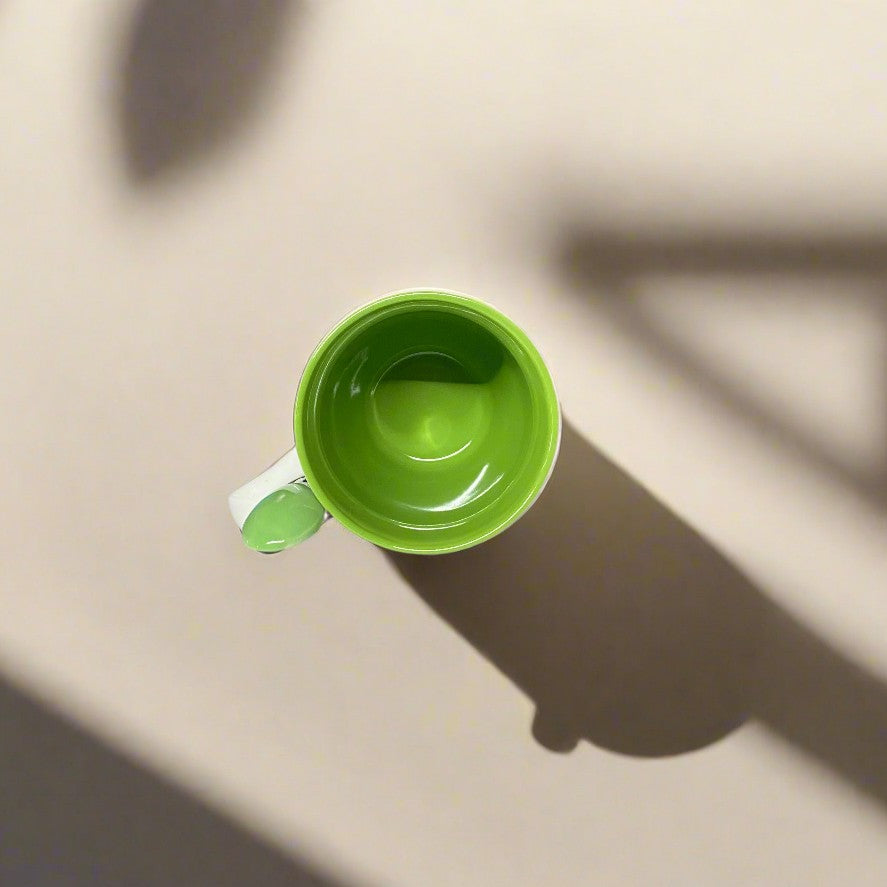 A vibrant green mug viewed from above, showcasing the bright interior. A subtle shadow casts on the surface, offering a minimalist souvenir design from Portugal, ideal for anyone seeking a colorful and simple Algarve-inspired keepsake.