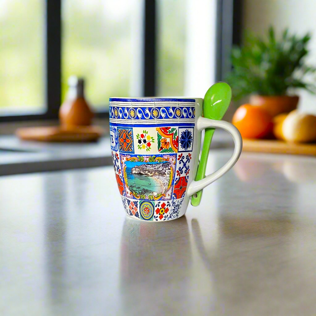 A beautifully decorated ceramic mug with colorful traditional Portuguese tiles and a small green spoon attached. This Algarve souvenir captures the region's iconic tile patterns, making it a perfect gift or personal memento.