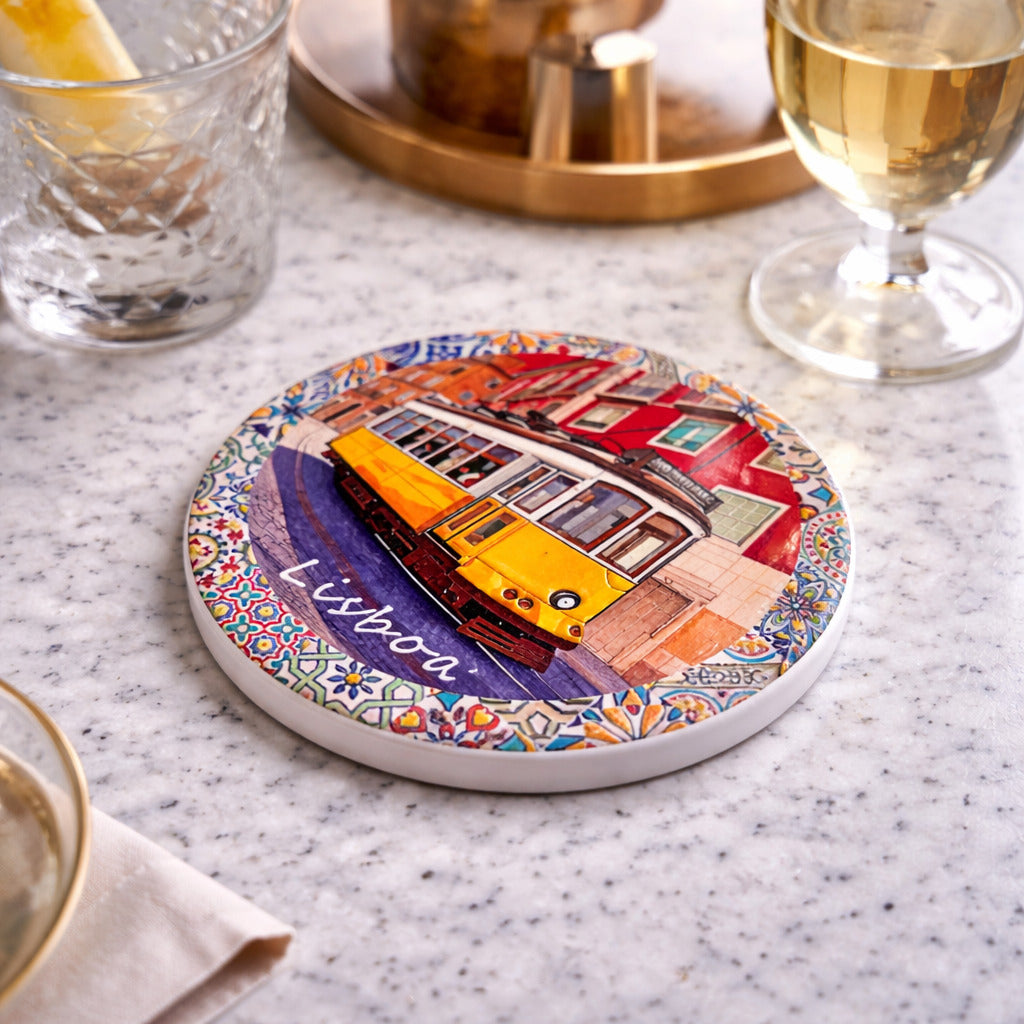 Lisbon ceramic coaster with yellow tram design placed on table with drinks in an elegant setting