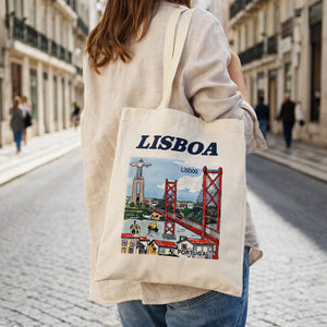 Lisbon cotton tote bag souvenir worn on shoulder featuring Lisboa illustration with 25 de Abril Bridge and Cristo Rei in Lisbon street setting.