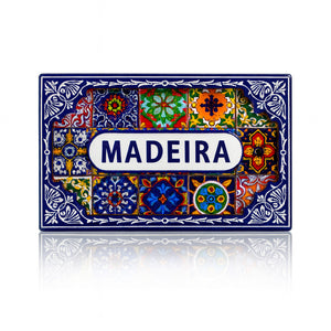 Rectangular magnet with the word "Madeira" centered on a white label, surrounded by multicolored Portuguese azulejo tile patterns and a decorative blue border