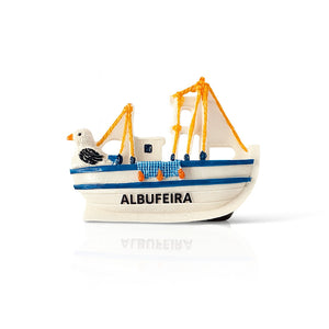 A resin magnet in the shape of a traditional fishing boat with blue-and-white stripes, orange rigging, and a seagull on top. The word 'ALBUFEIRA' is painted on the side of the boat.