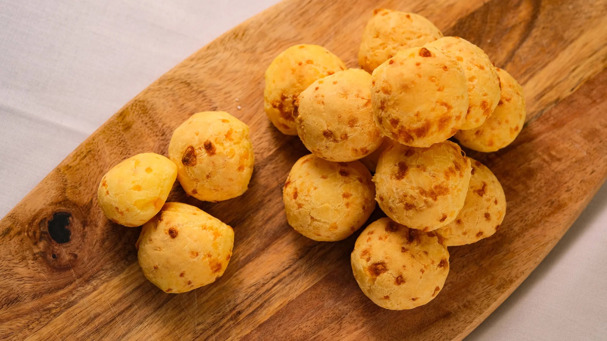 Close-up of Portugal cheese balls pão de queijo on wooden board with golden baked texture