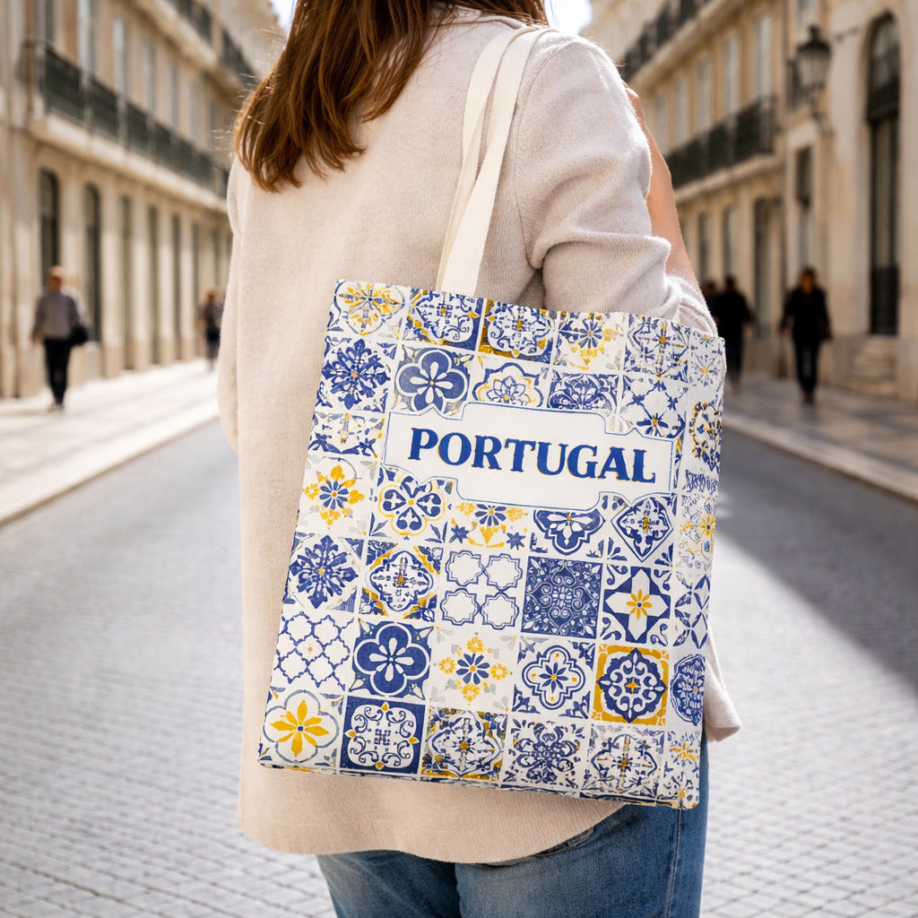 Person holding a tote bag with Portuguese tile design and 'Portugal' text on a street.