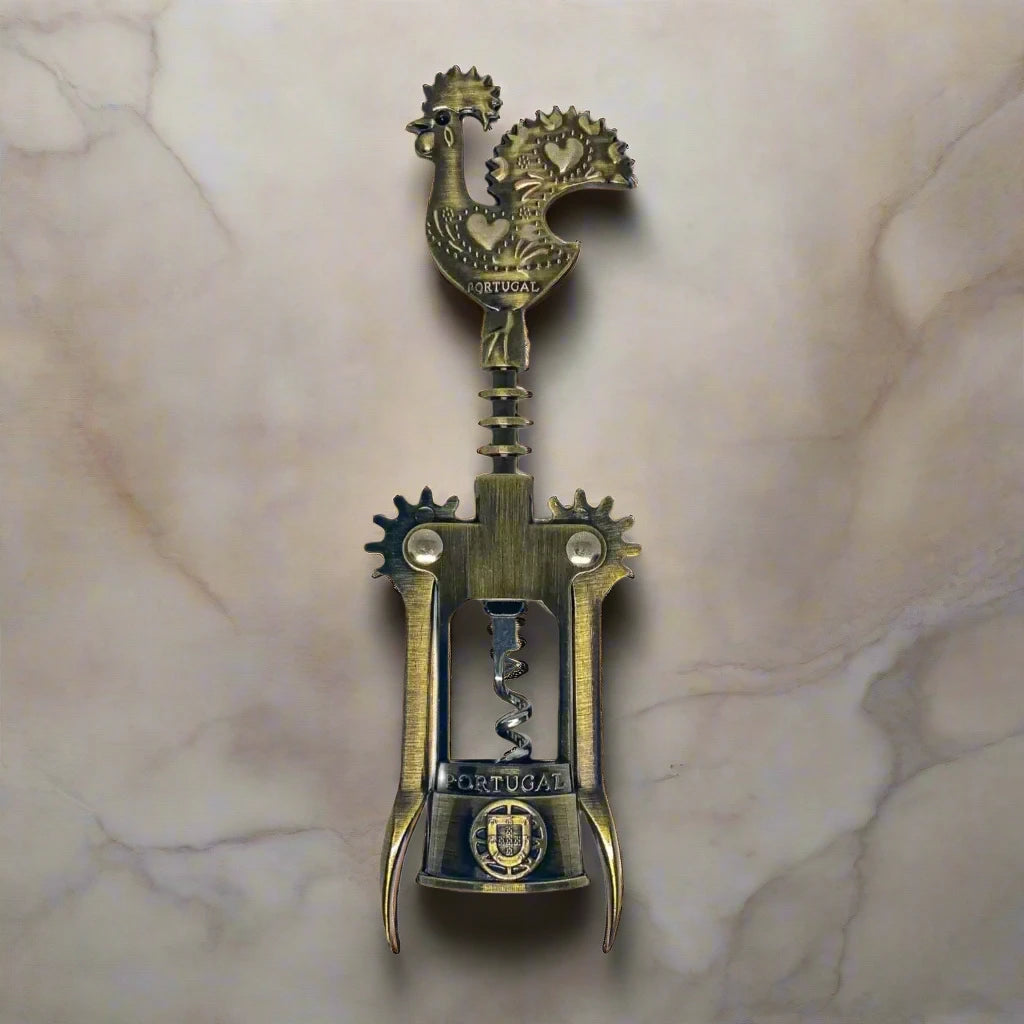 A detailed bronze corkscrew is depicted, featuring a handle shaped like the Barcelos Rooster, a well-known symbol of Portugal. The handle includes a heart design, and the midsection is inscribed with the word "Portugal." This elegant souvenir has two levers and a twisting mechanism.