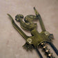 A bronze corkscrew with intricate craftsmanship is presented, with a handle modeled after the Barcelos Rooster, a symbol strongly linked to Portugal. The rooster's design incorporates a heart, and the word "Portugal" is etched into the midsection. The corkscrew includes two levers and a rotating mechanism.