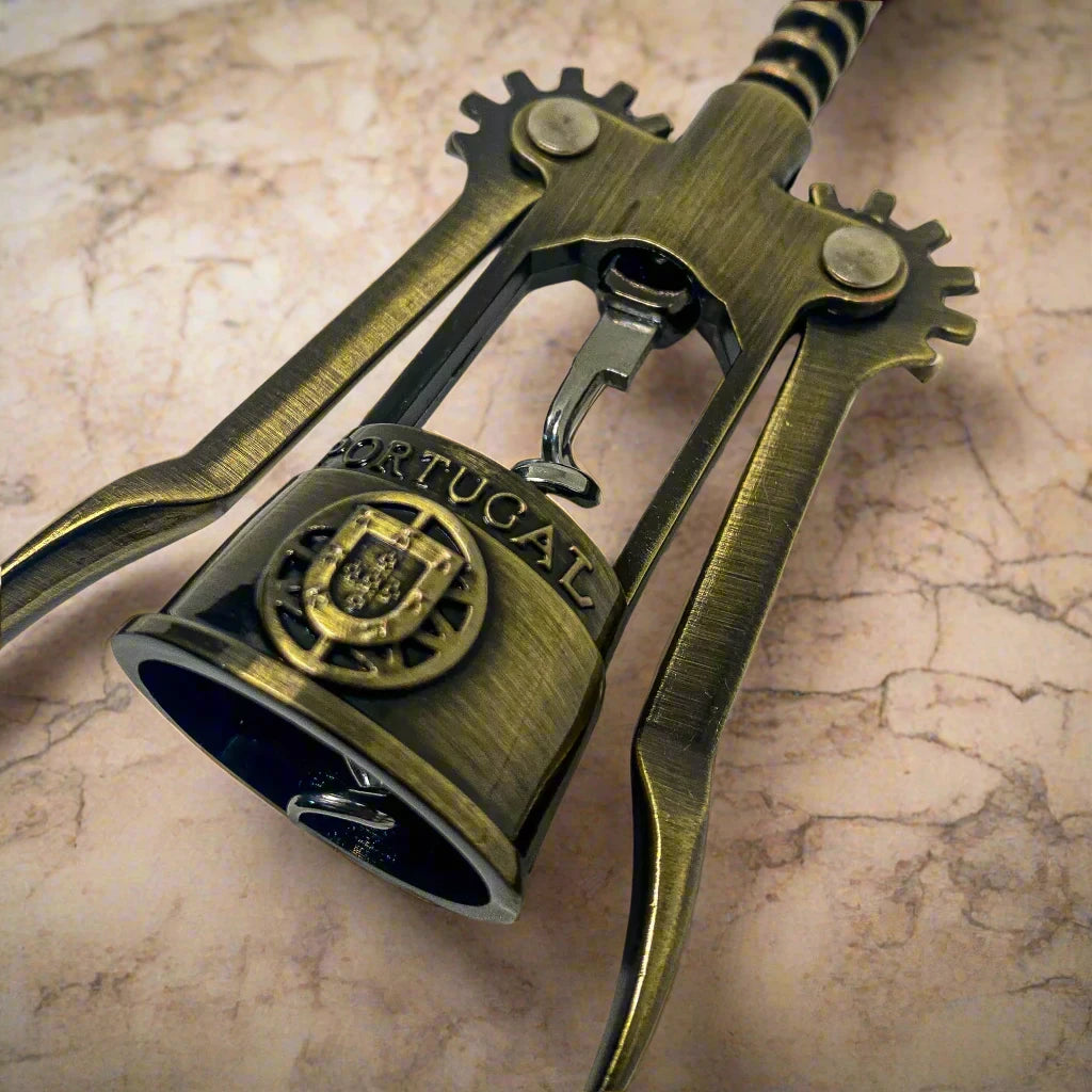 This bronze corkscrew features fine detailing and a handle shaped like the iconic Barcelos Rooster, often associated with Portuguese culture. The rooster handle includes a heart design, while the word "Portugal" is displayed on the midsection. The corkscrew is equipped with two levers and a twisting mechanism.