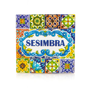 Square magnet with the name "Sesimbra" in blue letters, surrounded by traditional Portuguese azulejo tile patterns in bright colors, reflecting the town’s cultural style