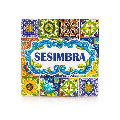 Square magnet with the name "Sesimbra" in blue letters, surrounded by traditional Portuguese azulejo tile patterns in bright colors, reflecting the town’s cultural style