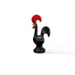 A black and red rooster figurine, a souvenir from Portugal, displayed on a table, symbolizing the Galo de Barcelos.