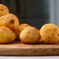 Batch of freshly baked Portugal cheese balls pão de queijo with golden crust on wooden board