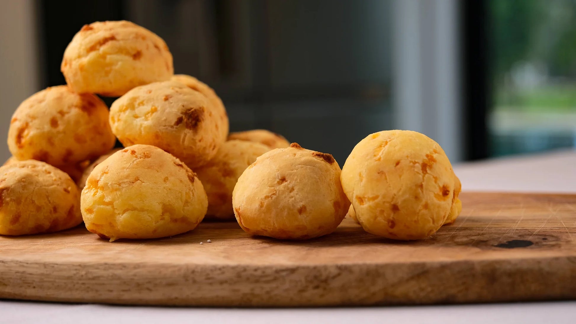 Batch of freshly baked Portugal cheese balls pão de queijo with golden crust on wooden board