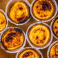 Group of freshly baked Lisbon pastel de nata with caramelized tops in aluminum molds